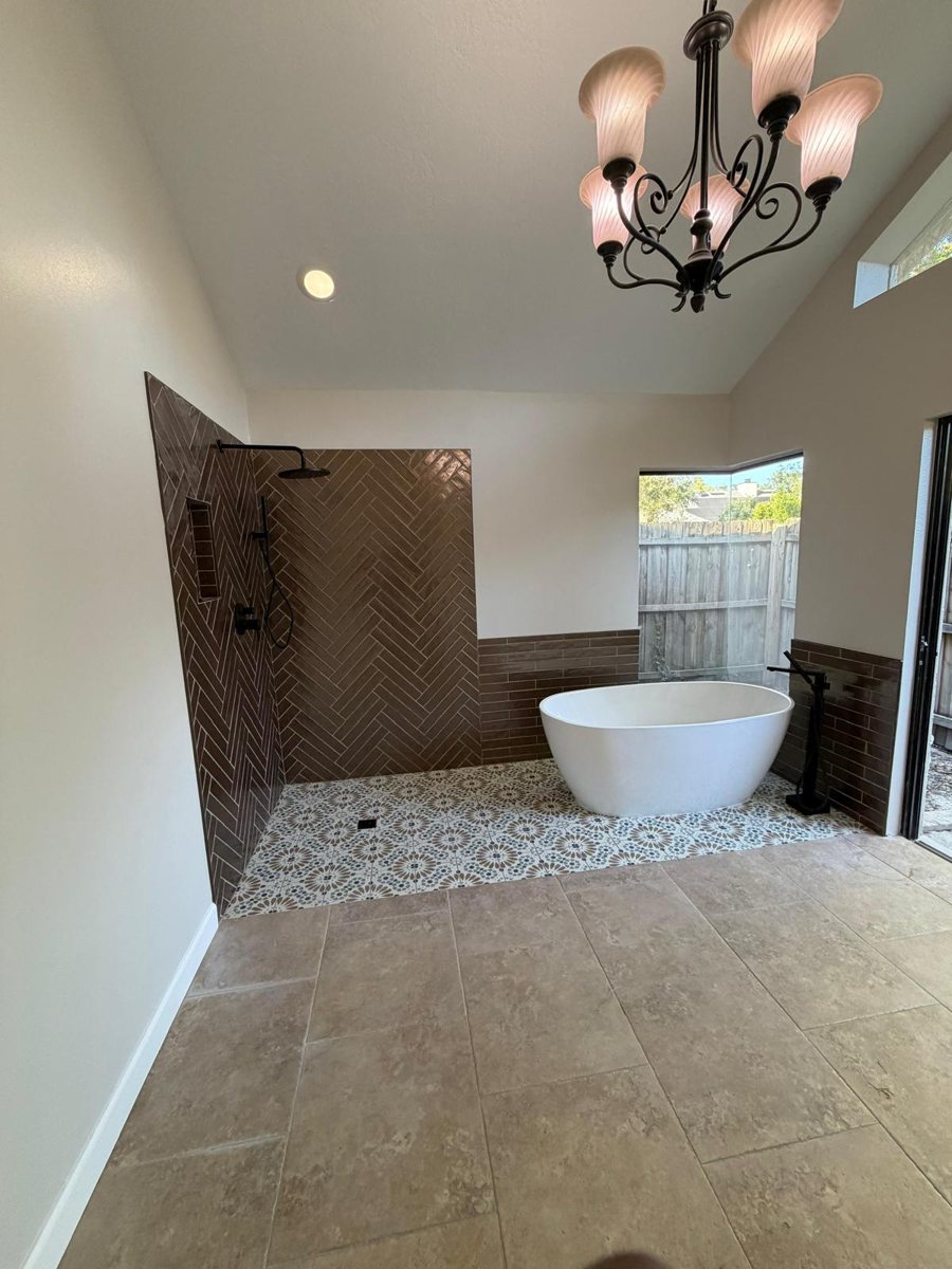 Primary bathroom renovation: dated tile shower and drop-in tub replaced with a herringbone walk-in shower and freestanding tub — after