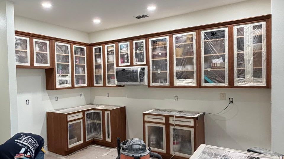 Kitchen cabinets refinished from dark wood to bright white with gold pulls — before