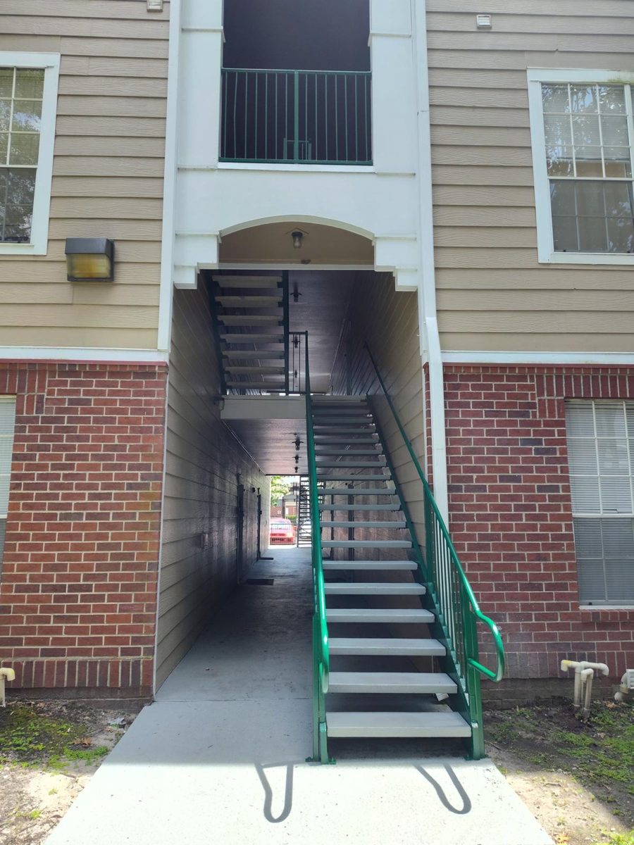 Apartment building breezeway and stairwell repainted, with siding, trim and green steel stair rails