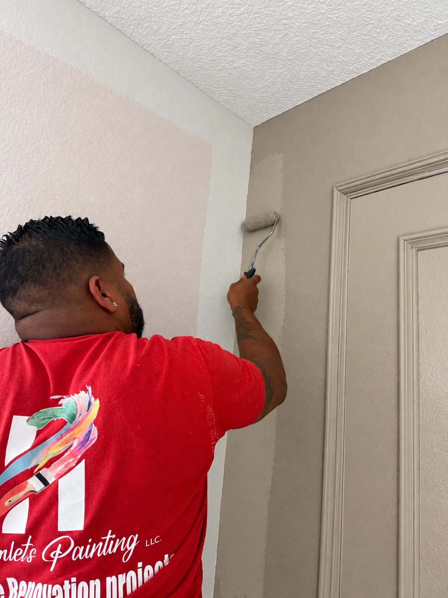 Hamlet's Painting crew member rolling a warm greige color onto a hallway wall