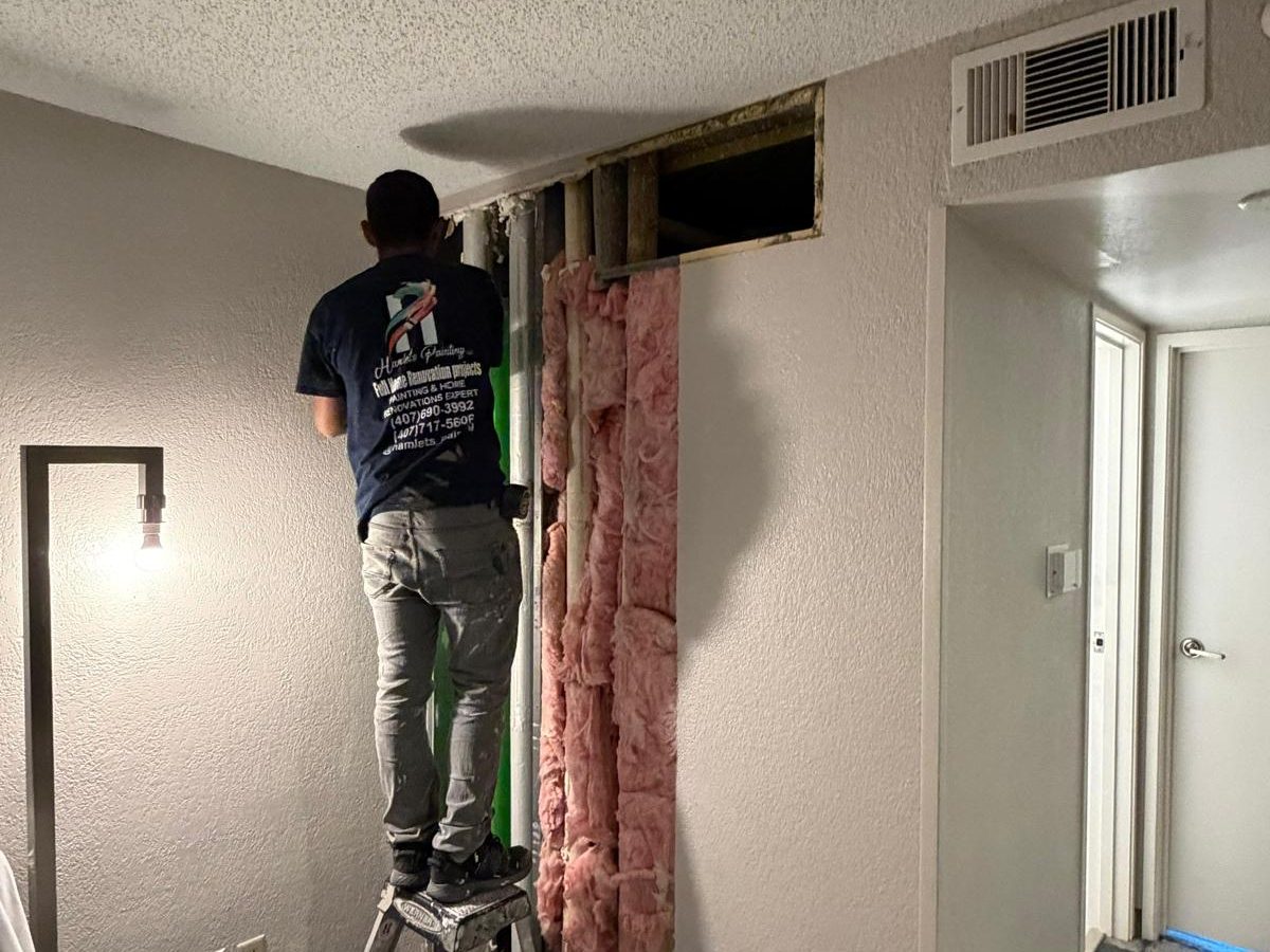 Hamlet repairing an opened drywall section in a Hilton hotel room