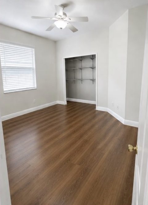 Bedroom carpet replaced with wood-look laminate flooring and fresh paint — after