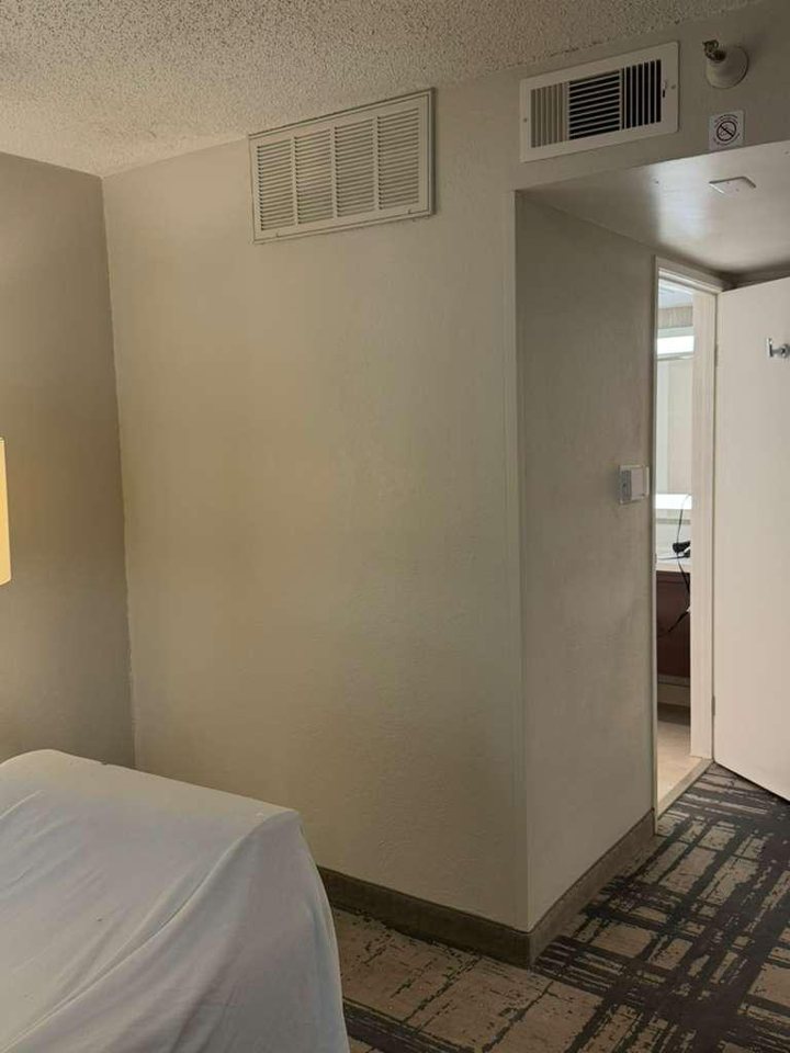 Hilton hotel room wall opened for drywall repair, then patched, textured and repainted — after