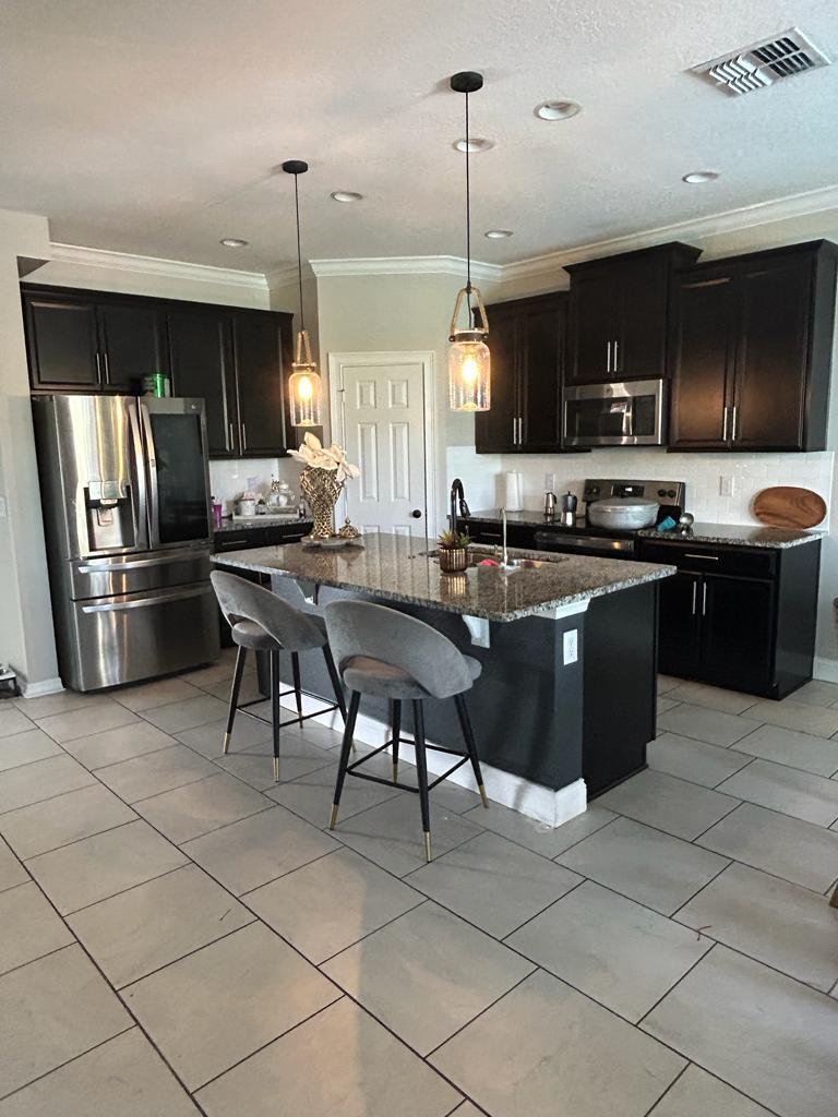 Kitchen cabinets painted from dark espresso to white with a charcoal island — before