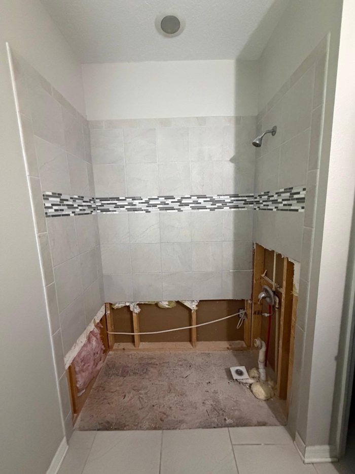 Old tiled shower with the pan and lower tile torn out